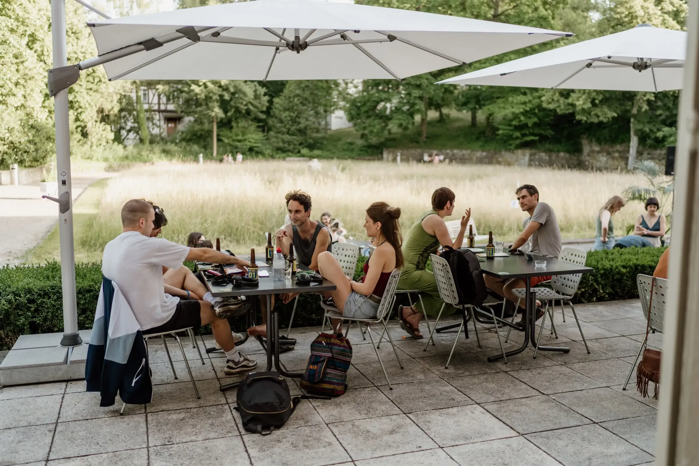 Gedeckte Tische unter Sonnenschirmen im Garten vor dem Friday