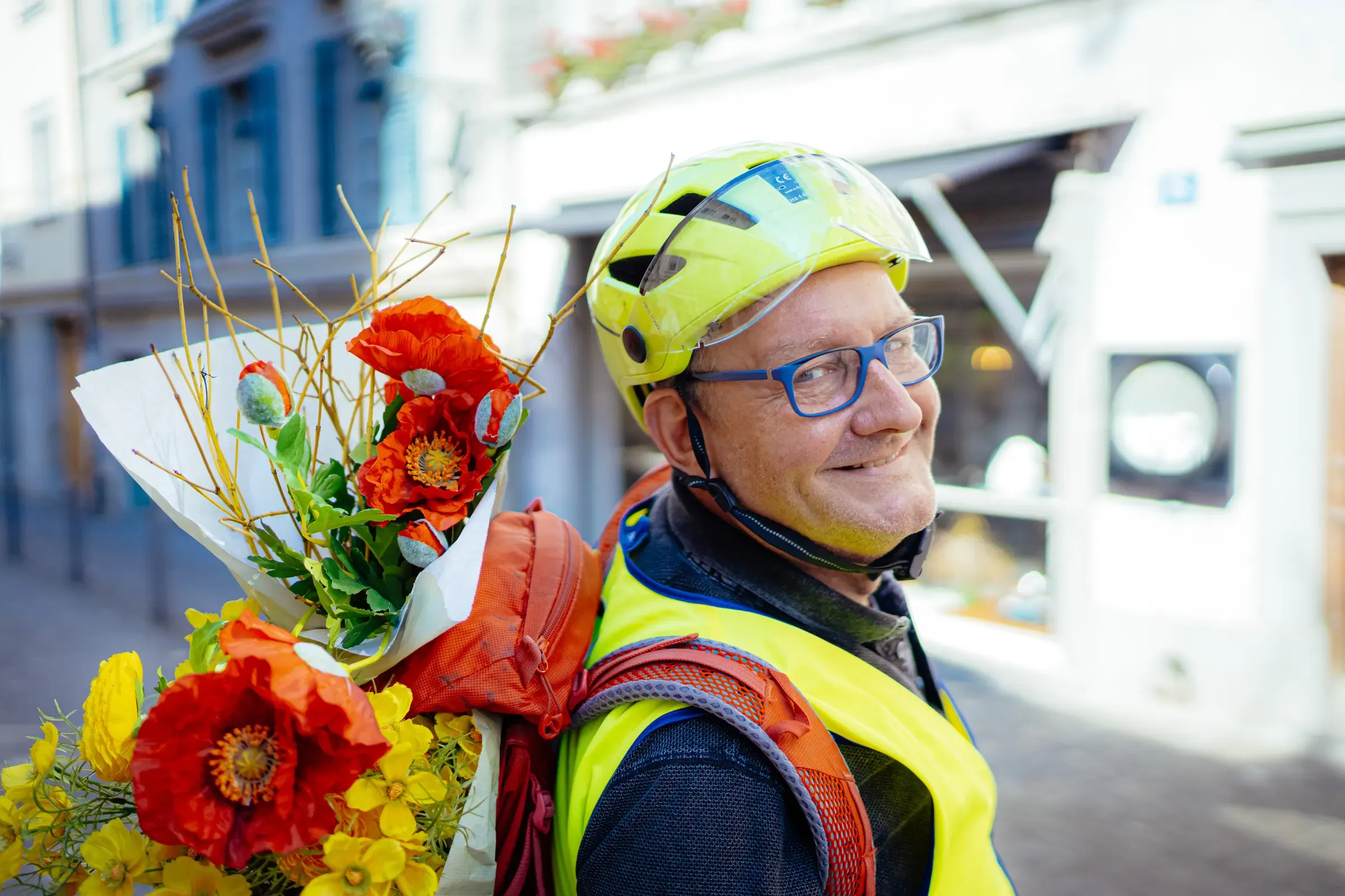 Olaf in Warnweste transportiert Blumensträusse im Velorucksack