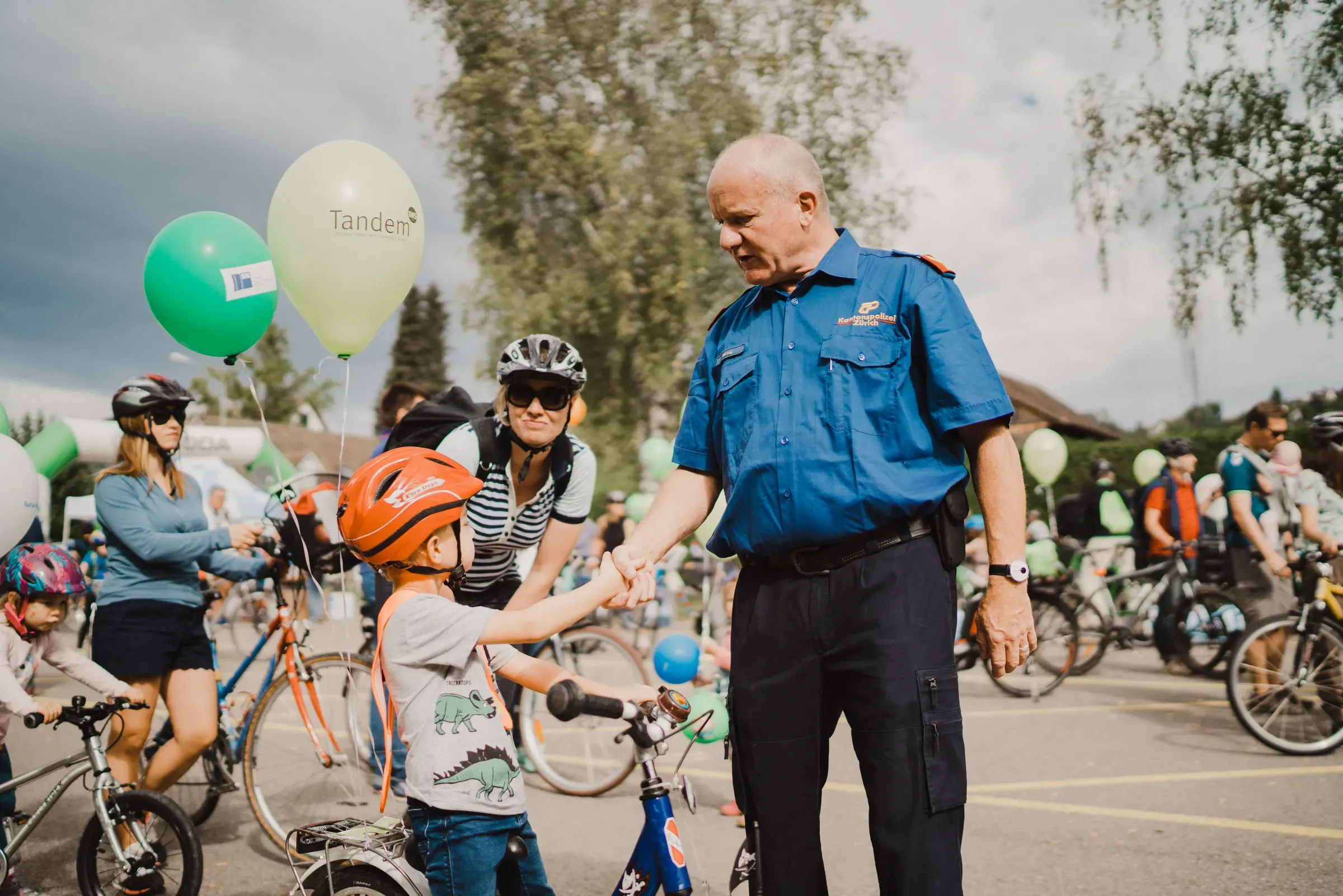 Polizist begrüsst Kinder auf ihren Velos am SlowUp